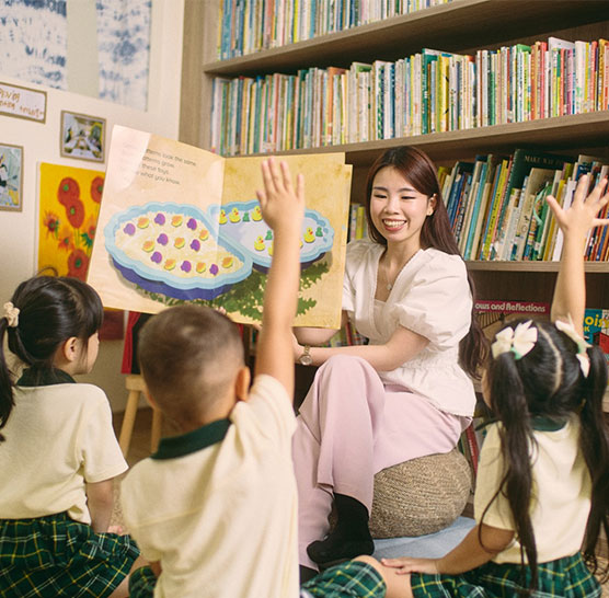 A teacher reading a picture book to a group of children in a Little Skool classroom